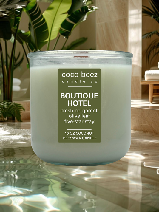A 10 oz coconut beeswax candle by Coco Beez Candle Co. in a clear glass jar, labeled 'Boutique Hotel'.