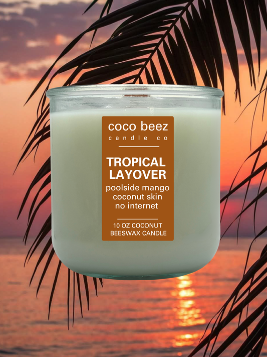A 10 oz coconut beeswax candle by Coco Beez Candle Co. in a clear glass jar, labeled 'Tropical Layover.
